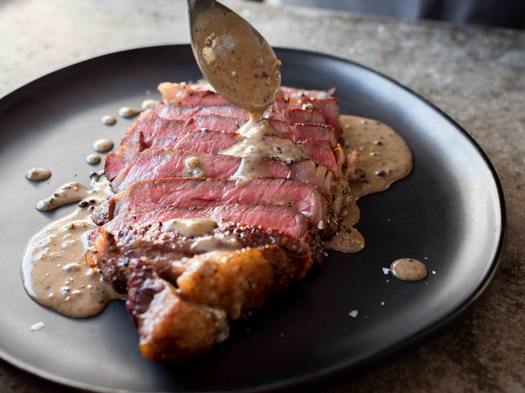 Plate and serve ribeye with creamy peppercorn sauce. Enjoy! 